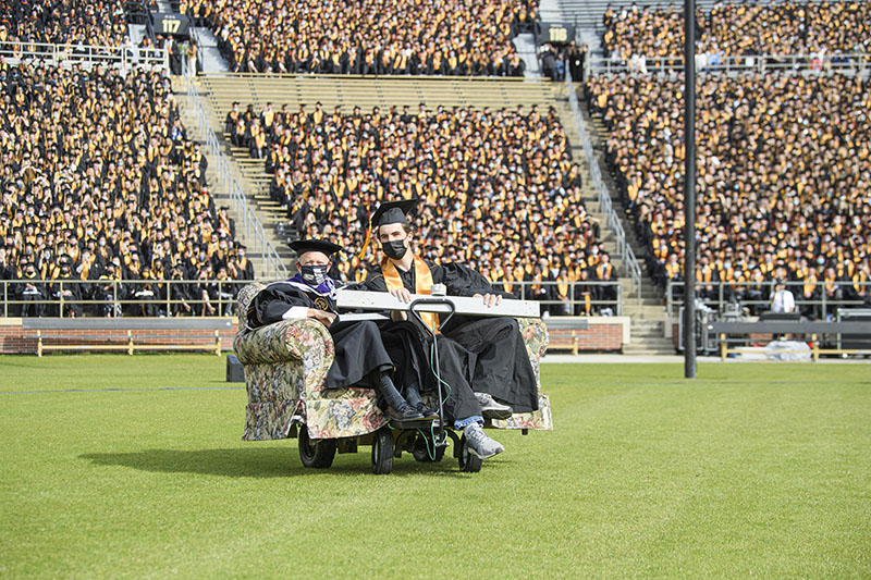 Mitch Daniels and Nathan Peercy drive around Ross-Ade Stadium on couch cart
