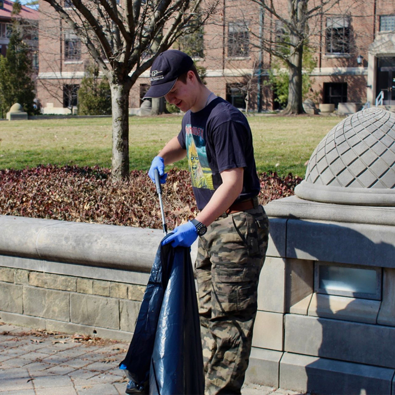 A photo of a green initiative club member picking up trash 