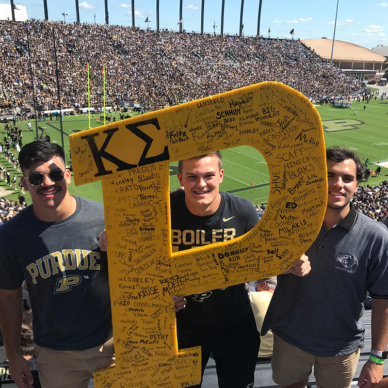 Kevin Boes with classmates holding a Purdue "P" sign at a football game.