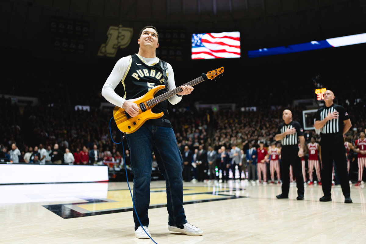 Noah Scott playing the National Anthem on the guitar at a basketball game.